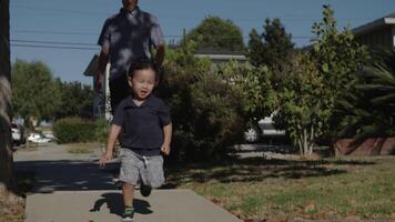 Slow motion of father on skateboard with son running ahead video