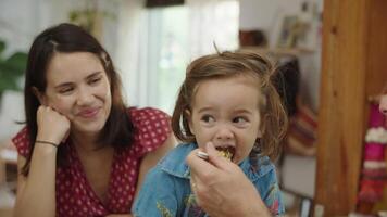 Ralenti du tout-petit nourri avec la mère qui regarde video