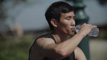 Cámara lenta de hombre adulto medio bebiendo agua después del ejercicio