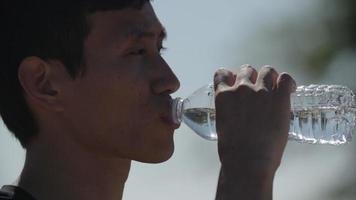 Cámara lenta de hombre adulto medio bebiendo agua después del ejercicio