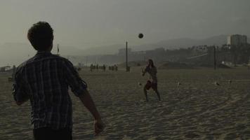 cámara lenta de hombres jugando con pelota en la playa