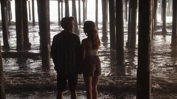 Slow motion of young couple standing under pier video