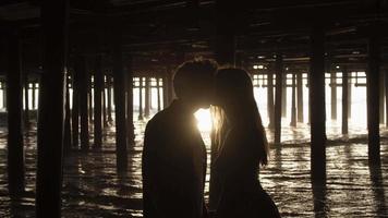 Zeitlupe des jungen Paares, das unter Pier küsst video