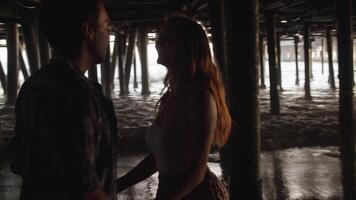 Slow motion of young couple kissing under pier video