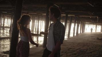 Slow motion of young couple dancing under pier