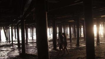 Slow motion of young couple walking under pier