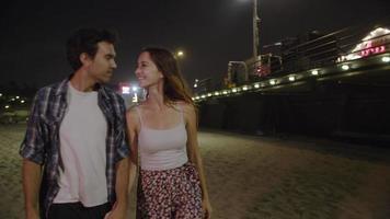 câmera lenta de um jovem casal caminhando casal de mãos dadas à noite video