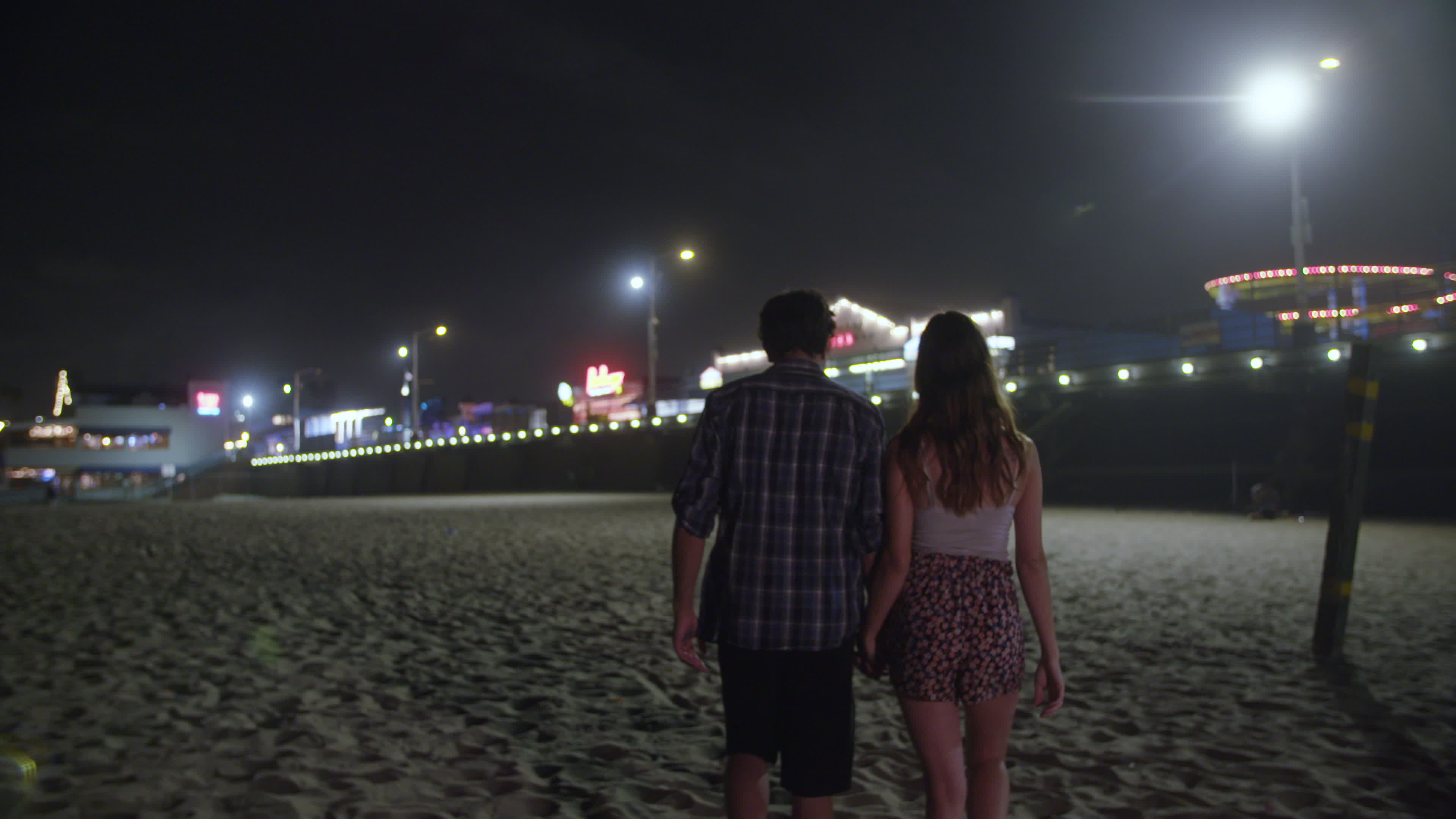 Cámara lenta de la joven pareja cogidos de la mano caminando en la playa  por la noche 1343170 Vídeo de stock en Vecteezy