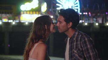 Zeitlupe des jungen Paares, das nachts mit Lichtern im Hintergrund küsst video