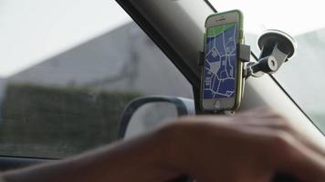 Cámara lenta del hombre usando la aplicación de navegación por satélite en el teléfono inteligente en el coche