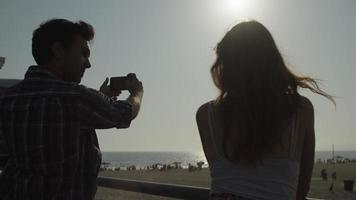 câmera lenta de homem tirando foto de praia com mulher