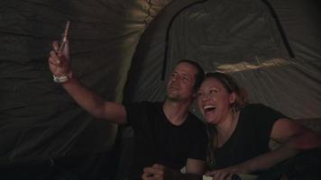 câmera lenta de casal sentado em uma barraca tirando uma selfie video