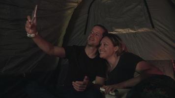 rallentatore di coppia seduta in tenda prendendo selfie
