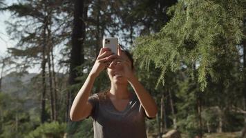 Slow motion of woman taking selfie on phone in forest video