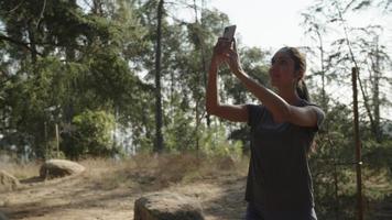 slow motion van vrouw die selfie op telefoon in bos