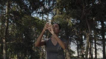 Slow motion of woman taking selfie on phone in forest