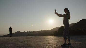 Zeitlupe der Frau, die Foto am Telefon bei Sonnenuntergang nimmt video