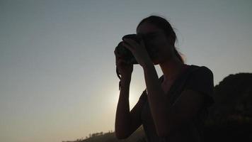 slow motion de femme prenant une photo avec appareil photo au coucher du soleil video