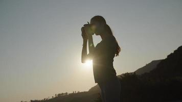 Zeitlupe der Frau, die Foto mit Kamera bei Sonnenuntergang nimmt