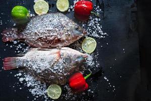 pescados de tilapia fresca con sal y condimentos foto
