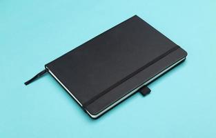 Black notebook isolated on blue background photo