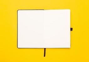 Black open notebook isolated on yellow background photo