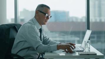 bejaarde zakenman kijken naar telefoon en werken met computer in moderne kantoren video
