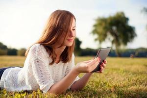 Beautiful young woman with digital tablet in park photo