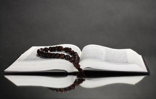 Biblia rusa y rosario de madera sobre fondo negro