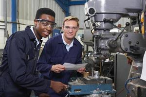 Engineer Showing Apprentice How to Use Drill In Factory photo