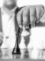 Monochrome shot of businessman beating chess king with pawn