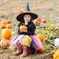 niña vistiendo traje de bruja de halloween en el huerto de calabazas