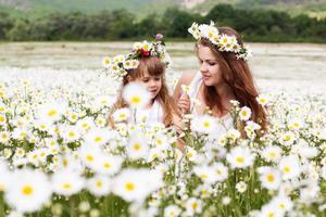 Mother with her child playing in camomile field photo