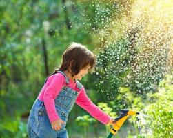 Little girl watering garden