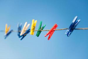 Colorful clothespins on clothesline against blue sky.