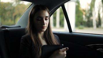 bella ragazza che guida in un taxi, legge il messaggio sul tablet