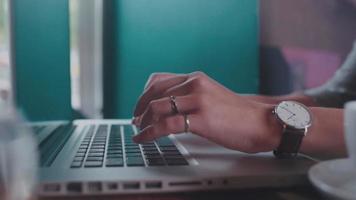 fechar-se. mão feminina com um relógio de pulso digitando em um teclado de laptop