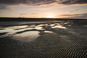 Vibrant sunrise landscape reflected in low tide water on beach photo