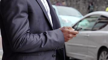 black businessman using smartphone app in the city with street in the back