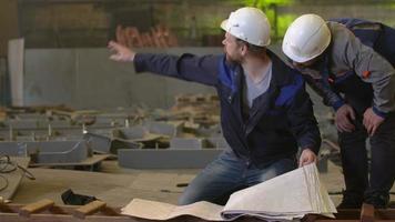 Ingenieure schauen sich Baupläne an und besprechen Bauphasen in der Schwerindustrie