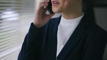 Confident businesswoman on call by blinds