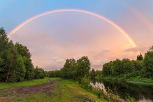 Hermoso arco iris doble sobre el río con camino sucio a lo largo