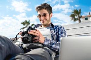 joven fotógrafo con laptop y cámara fotográfica foto