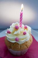 cupcake de celebración con decoración en rosa con fondo oscuro.