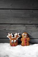 Christmas gingerbread biscuits on heap of snow against wooden background