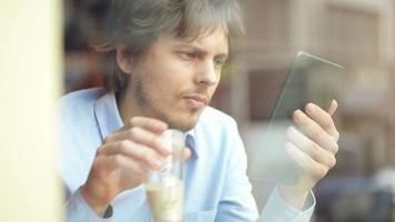 jonge man met behulp van digitale tablet koffie drinken