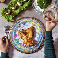 Woman holding white wine while seated at a meal photo