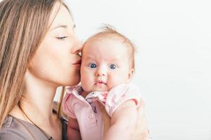 Happy mother kissing her baby at white background photo