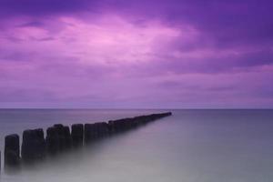 una hermosa vista de un océano brumoso con un cielo púrpura foto