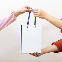 Woman giving a shopping bag to another person photo